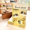 A copy of 'The Beach Birds', standing on top of six other copies, stacked horizontally.