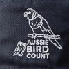 A close up of the Aussie Bird Count logo on the navy bucket hat. A close up of the Aussie Bird Count logo on the black bucket hat. The logo features a rainbow lorikeet sitting on a branch above 'Aussie Bird Count', adjacent to a small electronic device with a feather in front of it.