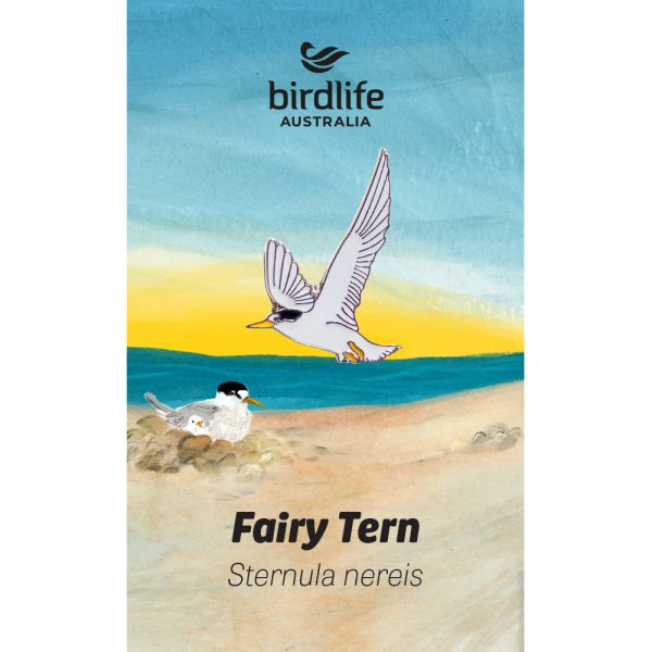 A pin of a Fairy Tern pin in flight, affixed to a backing card featuring a beach scene.