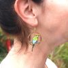 A Rainbow Bee-eater Earring hanging from a person's right ear.