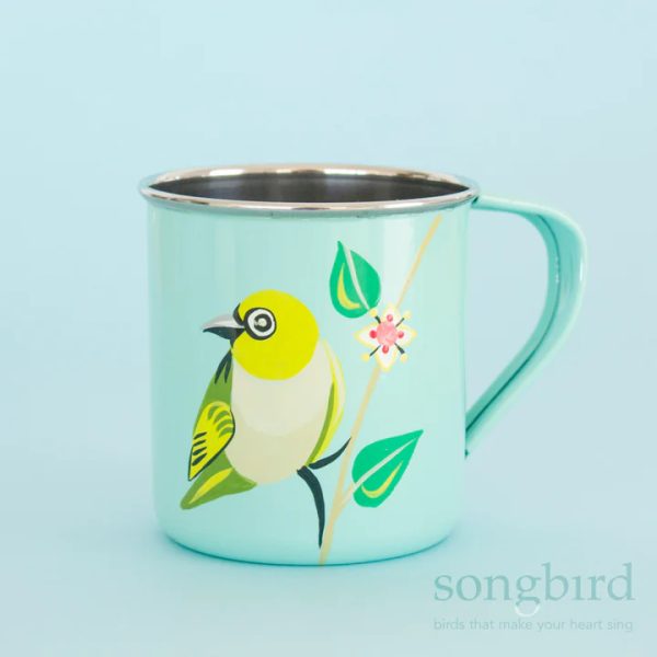A light blue metal mug with handpainted artwork of a Silvereye and Correa leaves and flowers. There is a watermark logo from the manufacturer, Songbird Collection, in the bottom right-hand corner.