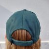 A BirdLife Australia bestie wearing a bottle green coloured cap. The back of the cap, displaying the adjustable velcro strap, is shown.