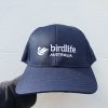 A navy coloured cap featuring a white embroidered BirdLife Australia logo, photographed in front of a neutral background.